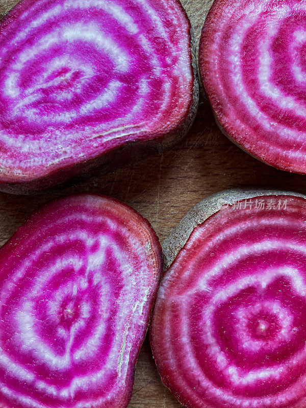全帧图像的行chioggia甜菜(Beta vulgaris)在木制砧板上，切片的甘蔗甜菜根切片显示同心粉红色和白色的环，上升的视图